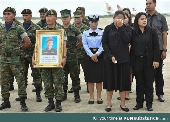 An honor guard holds up a picture of Samarn Kunan, 38, a diver who died working to save