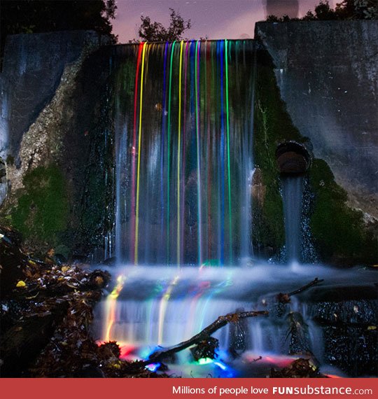 Long exposure shot of glow sticks dropped into a waterfall