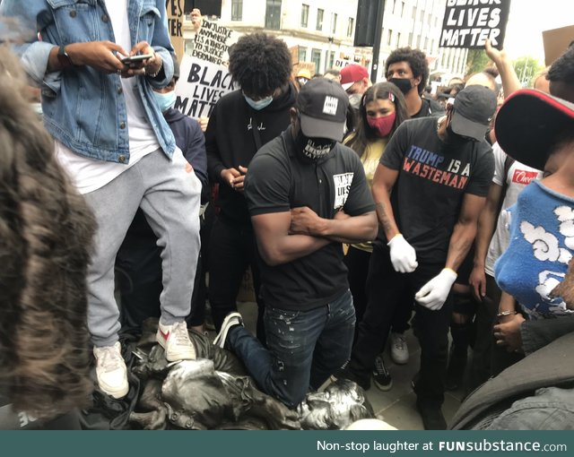 A protester in Bristol kneeling on the neck of a toppled statue of a 17th Century slave