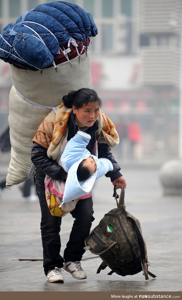 Luggage on her back and baby in her arm