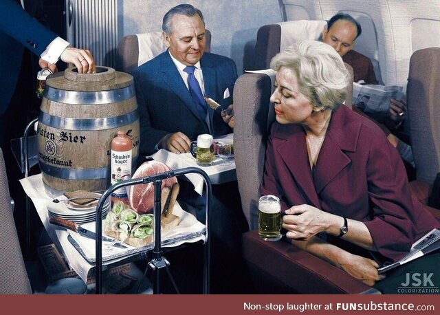 A Lufthansa flight attendant serves beer from a keg and ham during a flight in the 1960s