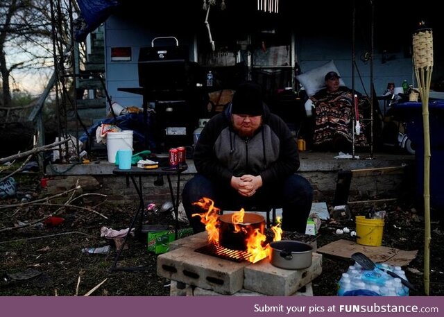 Tornado survivor sits by a fire outside his home to boil eggs and stay warm in Mayfield,