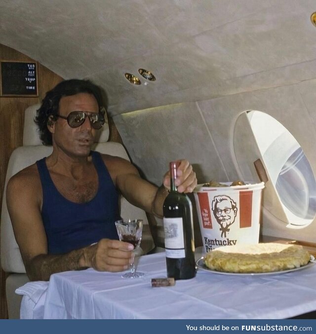 Julio Iglesias on his private jet with a bottle of wine and a bucket of KFC