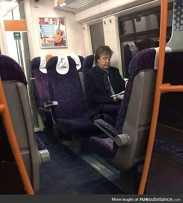 A man sitting on a train from London to Liverpool. His name is Sir Paul McCartney