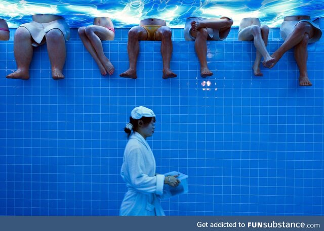 Waitress wearing a bathrobe walks by mannequins at a Beijing restaurant set to look like