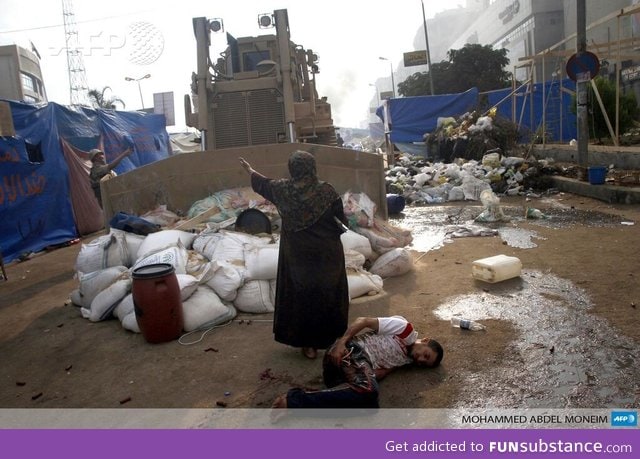 An Egyptian woman stands in front of bulldozer to protect an injured young man