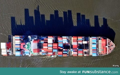 Cargo ships supply a city with goods. The shadow of this one looks like a cityscape