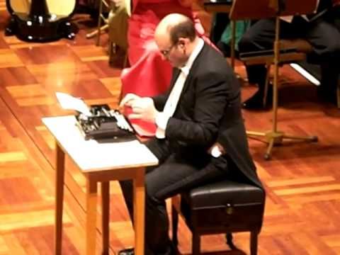 Guy plays typewriter as an instrument with orchestra