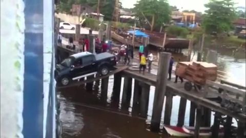 Car attempting to load on a ship over some planks