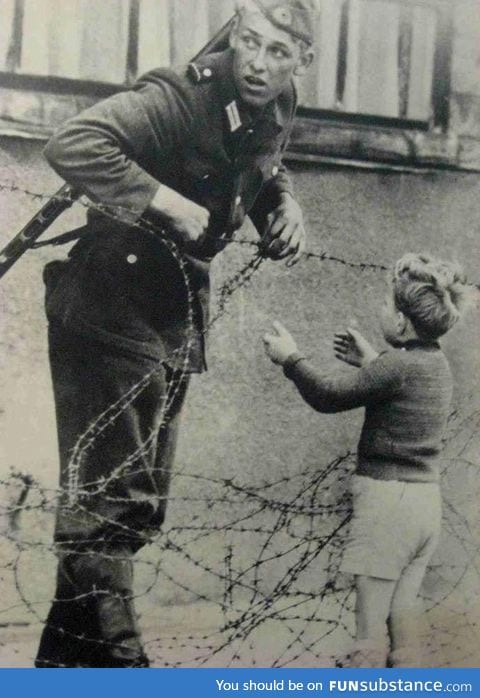 This moment.. An East German soldier ignores orders to let no one pass and helps a boy