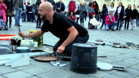 Street performer plays techno music on buckets and woks