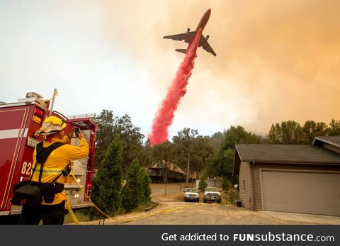 "An air tanker drops fire retardant on flames as firefighters continue to battle