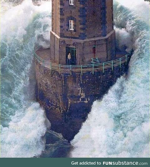A massive wave hits a lighthouse off the coast of France