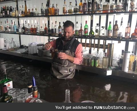 Owner pouring himself a drink after the rising Mississippi engulfed his bar in Davenport,