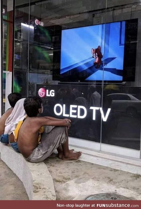 Shop owner in India playing cartoons on storefront display TV for kids to watch