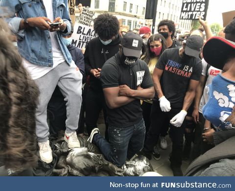 A protester in Bristol kneeling on the neck of a toppled statue of a 17th Century slave