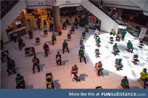 Food delivery drivers wait to pick up orders in “social distancing” chairs in