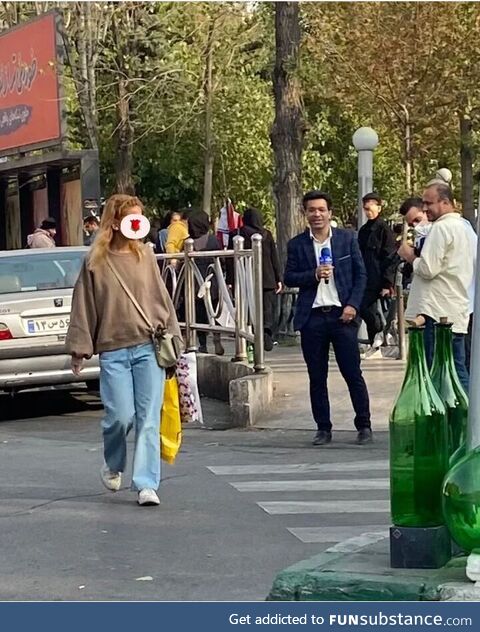 This Iranian lady without Hijab casually walking past Iranian state TV reporter