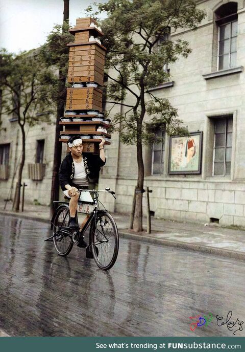 A Japanese man rides his bike carrying Soba noodles on his shoulder in