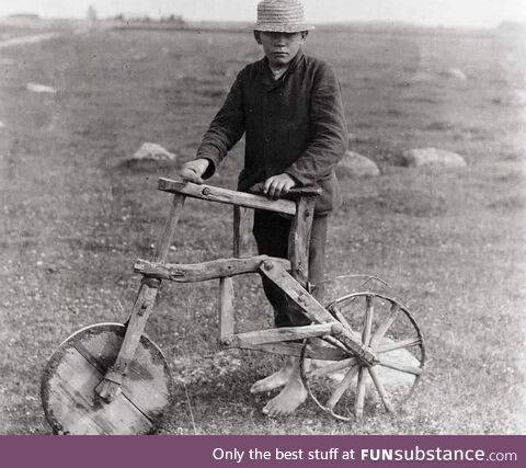 A kid with a self-made wooden bicycle, 1912