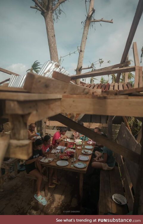 A family eats together amidst their wrecked home due to typhoon Odette