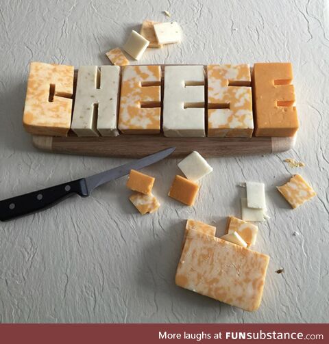The word “CHEESE” carved out of cheese