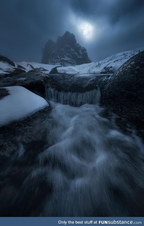 The sun breaking through the clouds over a rock structure in the Australian Alps