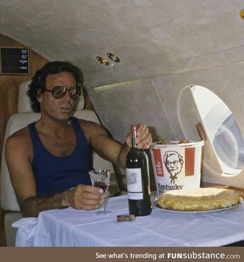 Julio Iglesias on his private jet with a bottle of wine and a bucket of KFC
