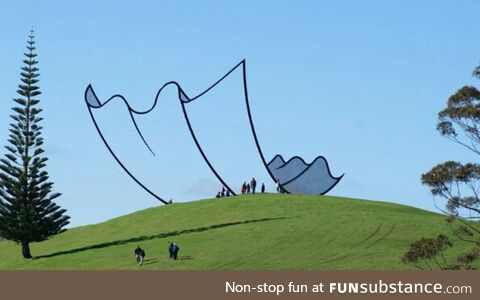 This Sculpture in New Zealand looks like a Cartoon piece of paper on top of the Hill