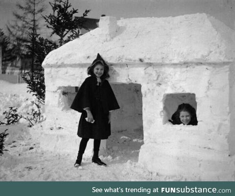 Two girls standing outside of a snow fort, 1910