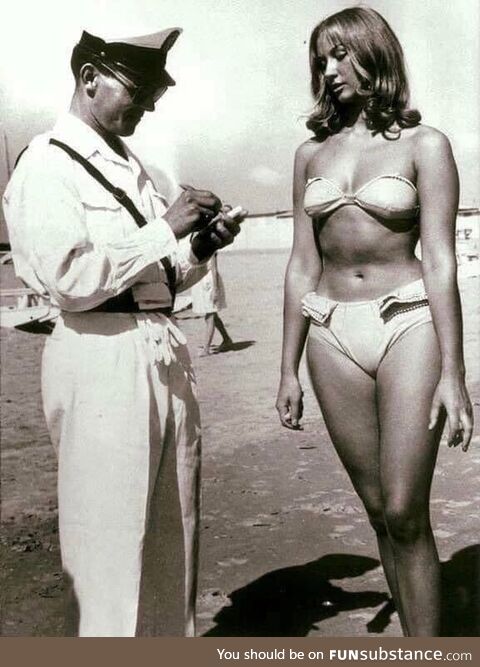 A police officer issuing a woman a ticket for wearing a bikini on a beach at Rimini,