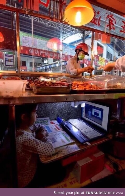 Chinese kid taking online class under her parents’ street food stand